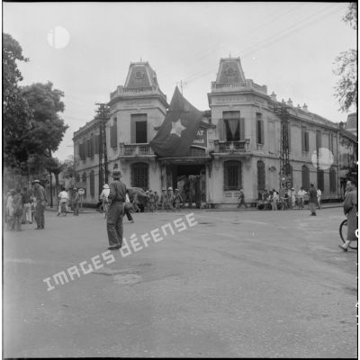 Le drapeau Viêt-minh flotte sur un bâtiment à l'architecture coloniale.