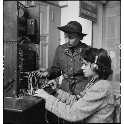 Un lieutenant du corps féminin des transmissions forme une élève à l'utilisation d'un central téléphonique dans un centre de formation.