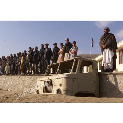 Habitants d'un village au nord de l'aéroport de Kaboul, chef de village et militaires afghans alignés.