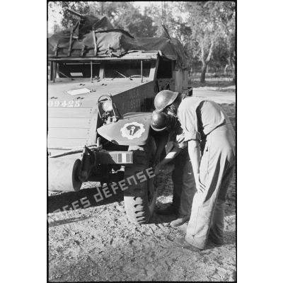 L'équipage du half-track M3 radio Fomalhaud du 2e escadron du 12e régiment de chasseurs d'Afrique (12e RCA) de la 2e division blindée (2e DB) examine une roue du véhicule.