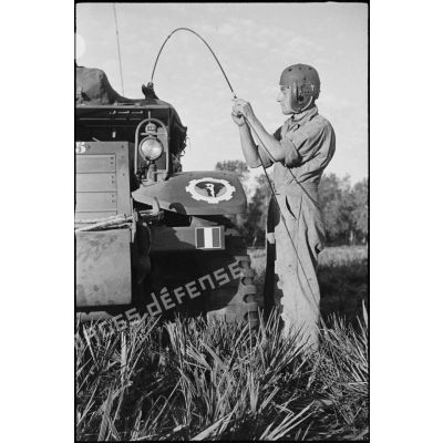 Un chasseur, membre d'équipage du half-track M3 radio Fomalhaud du 12e régiment de chasseurs d'Afrique (12e RCA)) de la 2e division blindée (2e DB), examine l'antenne radio de son véhicule.