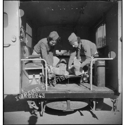 Deux conductrices ambulancières du 27e escadron du Train installent un blessé dans une ambulance Renault AGC 3.