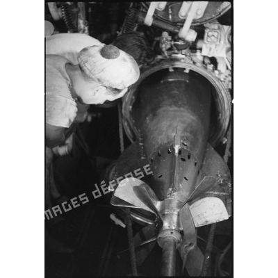 Dans la chambre des torpilles du sous-marin Casabianca, des sous-mariniers chargent une torpille de 550 ou de 400 mm dans un des tubes lance-torpilles.