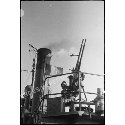 Marin servant une mitrailleuse double de 13,2 mm CA à bord d'un chalutier armé par la marine nationale dans le port d'Alger.