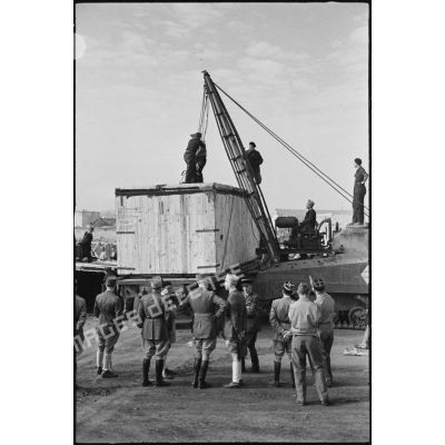 Déchargement d'une caisse de matériel américain, destiné aux troupes françaises, par une grue improvisée montée sur un char Sherman dans le port de Casablanca.
