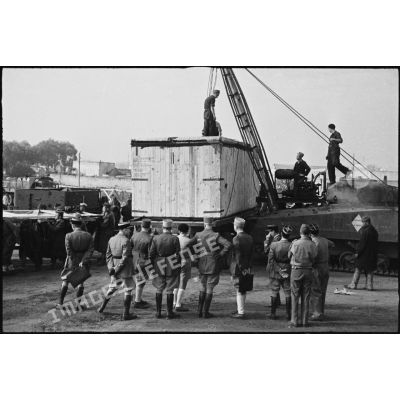 Déchargement d'une caisse de matériel américain, destiné aux troupes françaises, par une grue improvisée montée sur un char Sherman dans le port de Casablanca.