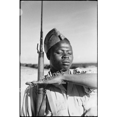Portrait d'un tirailleur sénégalais, équipé à la britannique, au présentez-armes lors d'une inspection.