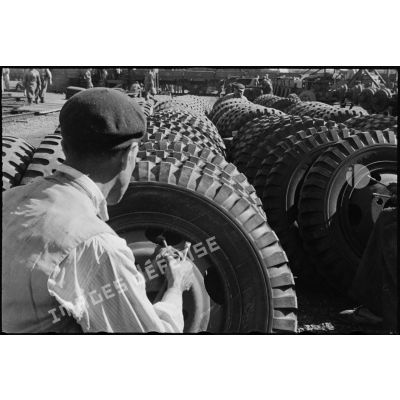 Vue de dos d'un civil gonflant un pneu de GMC à la chaîne de montage des camions d'Oran.