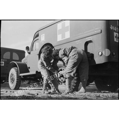 Changement d'une roue d'ambulance Dodge T215 par deux volontaires féminines conductrices à la 521e compagnie sanitaire.