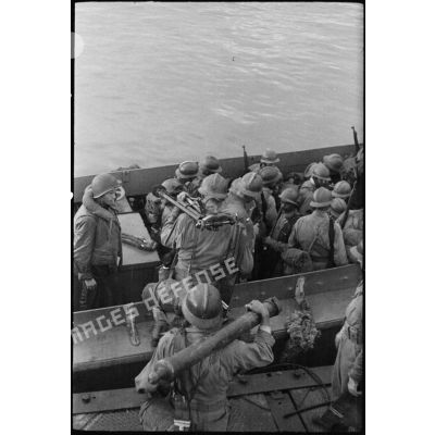 Des fantassins français embarquent à bord d'un LCVP conduit par un soldat américain.