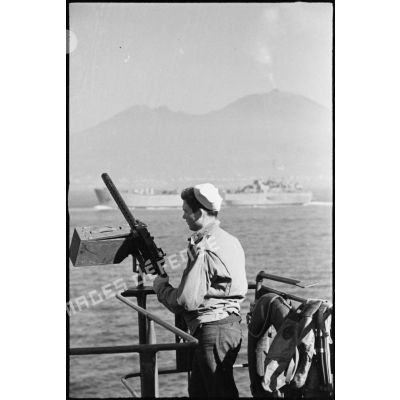 Un marin américain, servant d'une mitrailleuse antiaérienne, est à son poste de combat à bord d'un landing ship tanks qui approche des côtes italiennes.