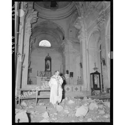 Un aumônier militaire catholique se trouve dans l'église, en partie détruite, d'un village situé à proximité des premières lignes italiennes.