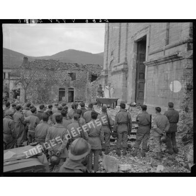 Des tirailleurs du 5e régiment de tirailleurs marocains (RTM) de la 2e division d'infanterie marocaine (DIM) assistent à la messe de Noël, célébrée par un aumônier militaire catholique sur le parvis de l'église d'un village situé à proximité des premières lignes italiennes.