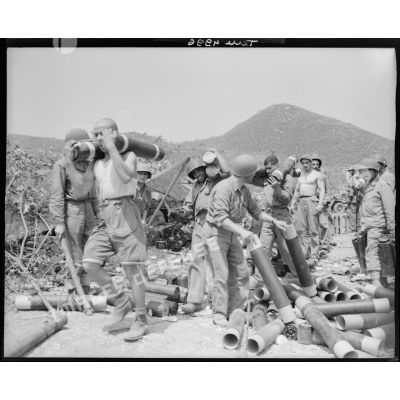 Des servants d'une unité d'artillerie transportent des obus de 105 mm dans leurs étuis.