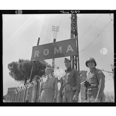 Le lieutenant general Mark Wayne Clark, commandant la Ve armée américaine, pose symboliquement avec deux de ses grands subordonnés devant un panneau indicateur aux portes de Rome libérée ; à droite, le major general Geoffrey Keyes, commandant le IIe corps d'armée.