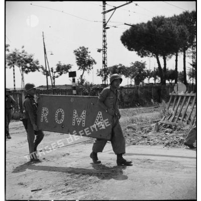 Deux soldats américains emmènent le panneau indicateur Roma en gare de Centocelle à Rome sur la route 6.