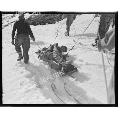 Transport d'un blessé par une formation d'éclaireurs-skieurs.