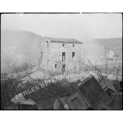 Une maison en ruines au milieu de la fumée et des bombardements.