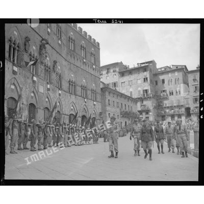 Lors d'une cérémonie, le général d'armée Alphonse Juin, commandant le corps expéditonnaire français (CEF), accompagnés de ses grands subordonnés, salue les drapeaux des unités alignés sur la Piazza del Campo à Sienne.