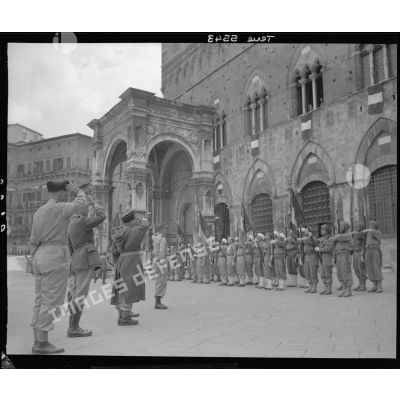 Lors d'une cérémonie, le général d'armée Alphonse Juin, commandant le corps expéditonnaire français (CEF), accompagnés de ses grands subordonnés, salue les drapeaux des unités alignés sur la Piazza del Campo à Sienne.