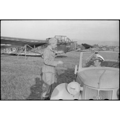 A bord d'un cabriolet Auto-Union, un capitaine (peut-être l'Hauptmann Joseph Karl) Gruppenkommandeure III./LLG.1 inspecte l'aérodrome de Valence-Chabeuil (Drôme) avant une mission.