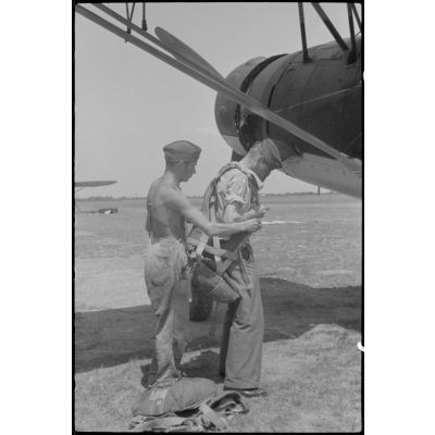 Un mécanicien de la 1re escadre aéroportée (Luftlandegeschwader 1) aide un pilote à s'équiper de son parachute avant qu'il monte dans un Henschel Hs-126.