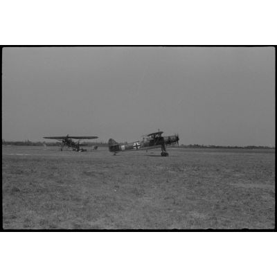 Sur un terrain d'aviation occupé par la 1re escadre aéroportée (Luftlandegeschwader 1), l'avion Henschel Hs-126 codé H4+NW s'apprête à décoller.