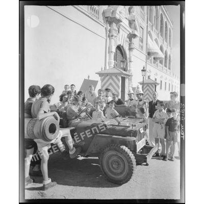 Une jeep Willys du service cinématographique de l'Armée (SCA) stationne devant le palais princier de Monaco.