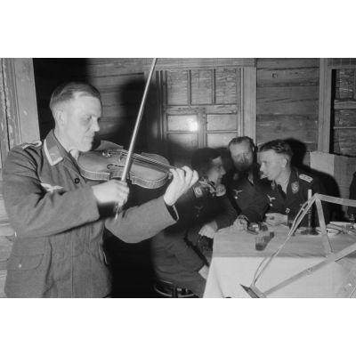 Des officiers de la Luftwaffe lors d'un repas, un sous-officier joue du violon.