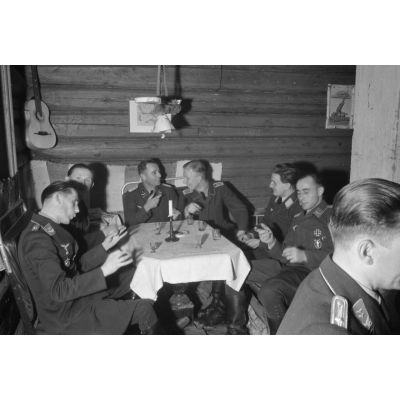 Des officiers de la Luftwaffe lors d'un repas, un sous-officier joue de l’accordéon.