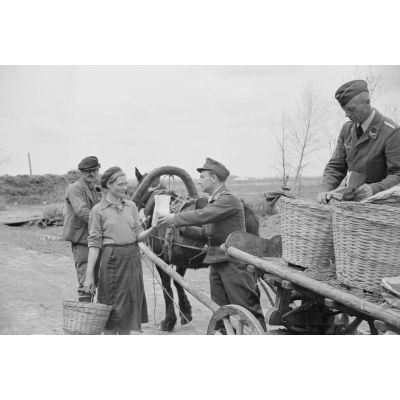 A l'entrée d'une exploitation agricole de la région de Smolensk, un Sonderführer de la Luftwaffe et un sous-lieutenant de la 1re compagnie de propagande contrôlent la sortie de denrées réquisitionnées.