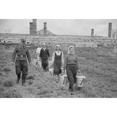 Sous la surveillance d'un caporal-chef de la Luftwaffe, des femmes russes travaillent dans une ferme réquisitionnée par l'armée allemande.