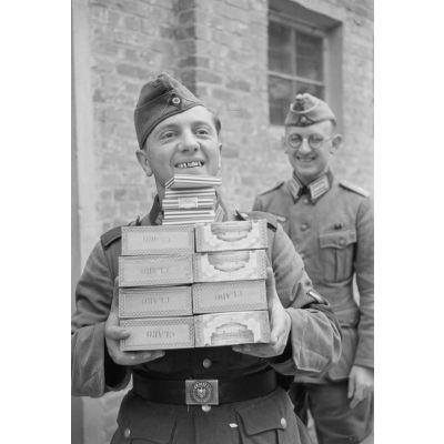 Un caporal de l'armée de terre (Gefreiter) reçoit des cigares et cigarettes de l'officier responsable du magasin d'approvisionnement.