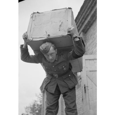Un caporal de l'armée de terre (Gefreiter) récupère une caisse dans un magasin d'approvisionnement de l'armée de terre allemande.
