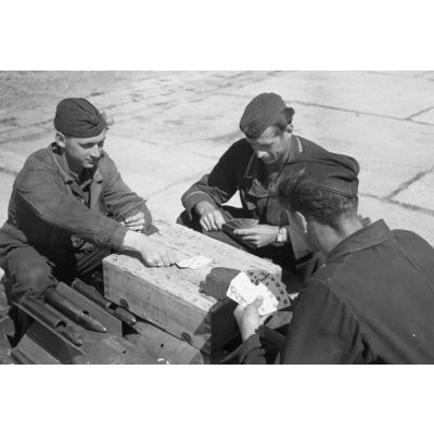 Des mécaniciens du Kampfgeschwader 3 Blitz jouent aux cartes sur une caisse de munitions.