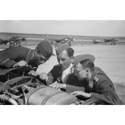 Un mécanicien et deux officiers s'affairent sur l'un des moteurs BMW d'un bombardier Ju-88 du Kampfgeschwader 3 Blitz.