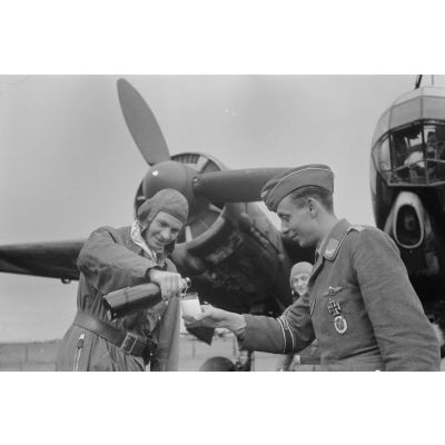 Un officier pilote de bombardier Junkers Ju-88 du Kampfgeschwader 3 verse un verre de Champagne à un reporter de la 1re compagnie de propagande de l'armée de l'air allemande (Luftwaffe Kriegsberichter Kompanie).