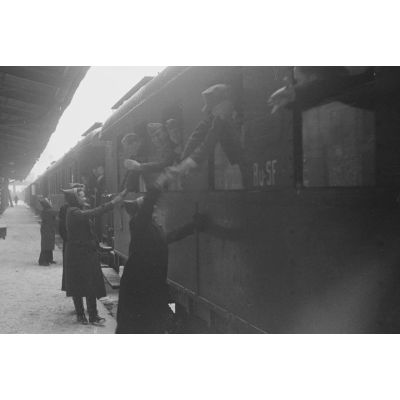 Sur le quai d'une gare, des permissionnaires allemands rejoignent leur affectation, des volontaires féminines saluent des officiers.