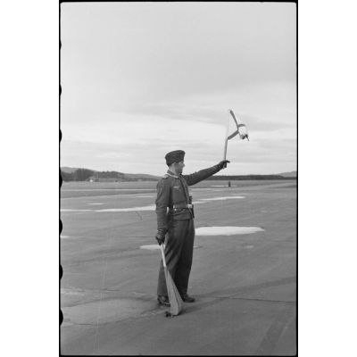 En Norvège, sur le terrain de Banak où stationne le 8./LLG 1 (Lulftlandegeschwader 1), un adjudant-chef (Oberfeldwebel) donne le signal du décollage des avions.