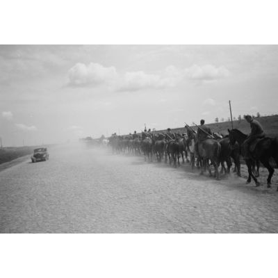 Des cavaliers allemands progressent sur une route pavée.