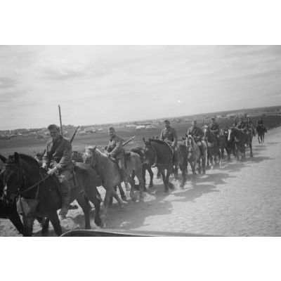 Des cavaliers allemands progressent sur une route pavée.