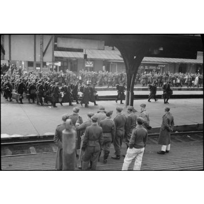 Lors d'un arrêt dans une gare, des personnels du 8./Luftlande-geschwader 1 (8./LLG1) assistent au ballet des persmissionnaires sur le quai.
