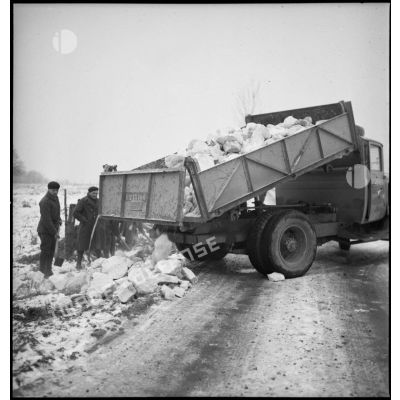 Des pionniers d'une unité de la 55e DI (division d'infanterie) déchargent des pierres extraites d'une carrière de la benne d'un camion Citroën type 45 pour la réfection d'une route.