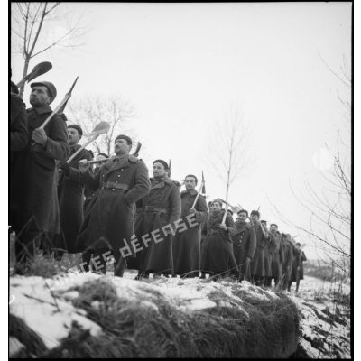 Après avoir travaillé à la réfection d'une route, des pionniers d'une unité de la 55e DI (division d'infanterie) sont rassemblés en ordre serré.