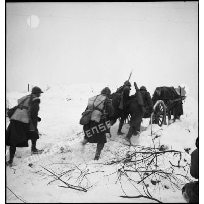 Des soldats de la 2e armée en patrouille poussent dans la neige une voiturette porte-munitions hippomobile.
