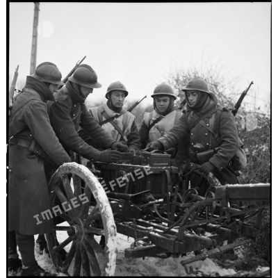 Des soldats de la 2e armée en patrouille poussent dans la neige une voiturette porte-munitions hippomobile.