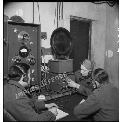 Des sapeurs radiotélégraphistes du 202e BGF (bataillon du génie de forteresse) suivent l'instruction d'un caporal du 8e RG (régiment du génie) sur un poste de radio dans la salle radio de l'ouvrage du Hackenberg de la ligne Maginot.