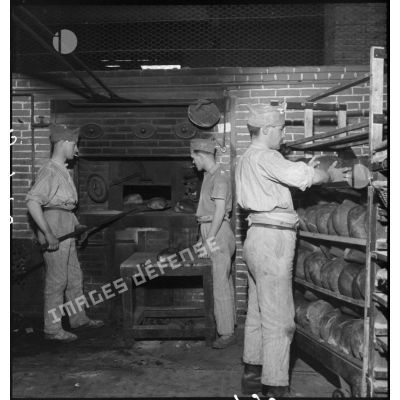 Des soldats boulangers enfournent des pains dans un four dans une boulangerie de l'intendance militaire.