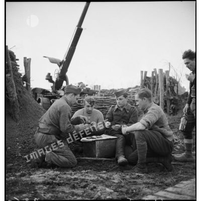 Photographie de groupe d'artilleurs du 402e RAAA qui jouent aux cartes dans leur poste de combat.
