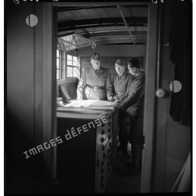 Des officiers de l'artillerie lourde sur voie ferrée (ALVF) tiennent une réunion dans un wagon.